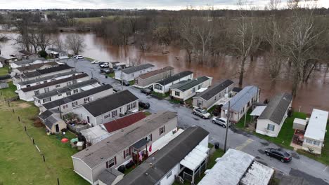 Mobile-home-trailer-park-with-flooded-river-in-background-during-winter