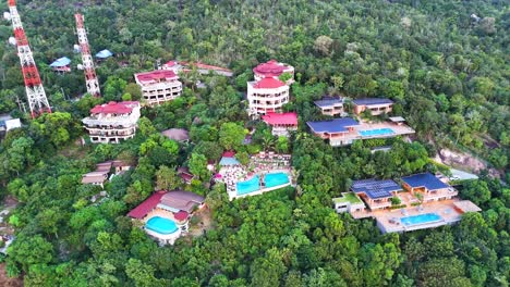 Tropical-resort-buildings-surrounded-with-jungle-forest,-aerial-view
