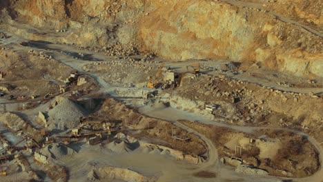 Stone-quarry-aerial-close-up-shot-showing-winding-roads-and-heavy-machinery