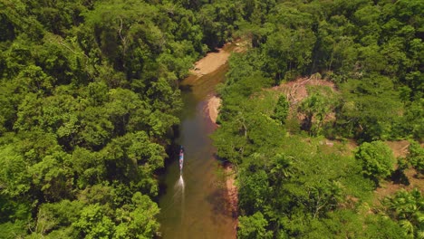 A-boat-navigating-a-winding-river-in-oxapampa,-peru's-lush-jungle,-during-daylight,-aerial-view