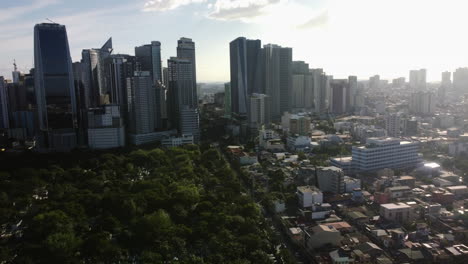 Drone-tilting-over-the-south-cemetary,-toward-the-Makati-skyline-in-Manila,-Philippines
