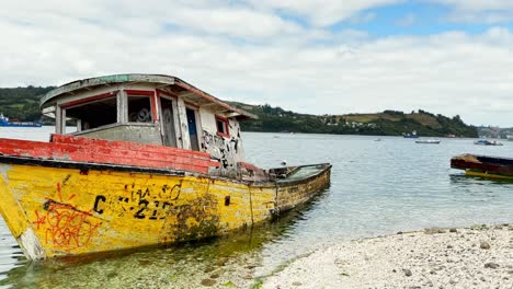Abandoned-typical-boat-moored-at-Dalcahue-Shoreline-,-Pan-shot