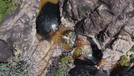 Antena-Desciende-Hacia-Una-Mujer-En-Una-Pequeña-Piscina-Con-Cascada-En-Bolivia