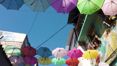 Walking-under-colorful-umbrellas-above-the-streets-of-La-Candelaria,-sunny-Bogota