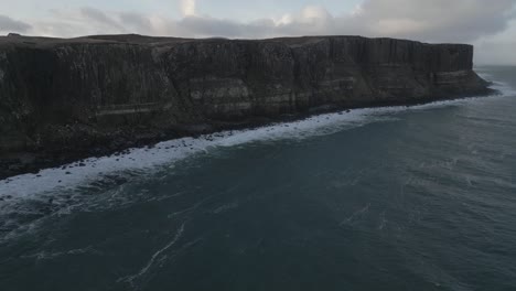 Kilt-rock,-scotland-with-dramatic-cliffs-and-waves-crashing,-overcast-sky,-aerial-view