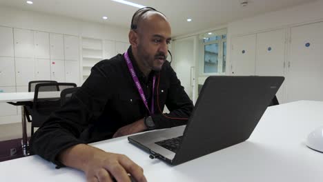 Bearded-Asian-customer-service-advisor-communicating-with-clients-on-office-laptop