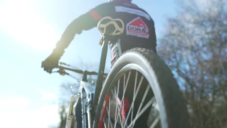 Low-angle-shot-of-a-mountain-biker-walking-with-his-bike-under-a-clear-sky