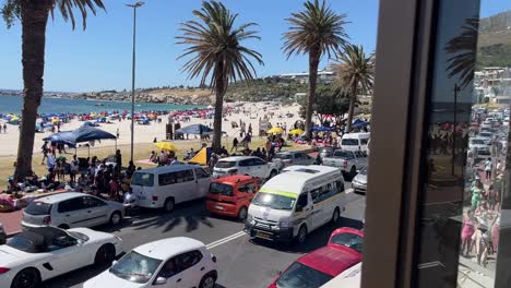 Cape-Town,-South-Africa,-a-busy-street-along-a-beach-full-of-people