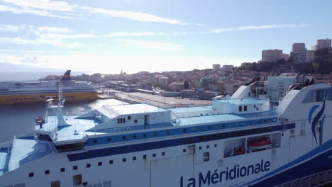 Vuelo-Aéreo-Hacia-Atrás-Desde-Ajaccio-En-Un-Día-Soleado,-Revelando-Un-Crucero-Atracado