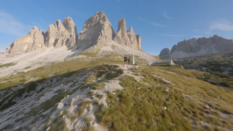 Two-friends-admire-landscape-of-Dolomites,-aerial-FPV-fly-by-view
