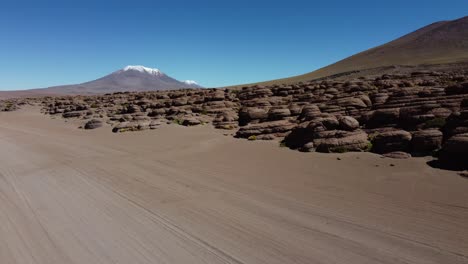 Aerial-follows-vehicle-tracks-in-desert-sand,-high-Bolivian-altiplano
