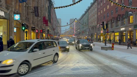 Verschneiter-Abend-In-Stockholm-Mit-Festlichen-Lichtern-Und-Geschäftigem-Straßenleben,-Kungsgatan-Zu-Weihnachten-Geschmückt