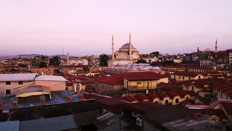 Forward-drone-shot-of-Nuru-Osmaniye-Mosque-with-view-of-roofs-of-buildings-and-cityscape-at-background-during-sunset-in-Istanbul