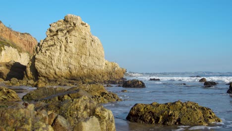 Waves-crashing-in-slow-motion-on-the-shore-of-El-Matador-Beach-at-golden-hour-in-Malibu,-California