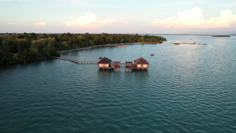 Langer-Holzsteg,-Der-Zu-Zwei-Überwasserbungalows-Führt,-Bei-Sonnenuntergang-Auf-Der-Insel-Leebong,-Belitung,-Indonesien---Luftparallaxe