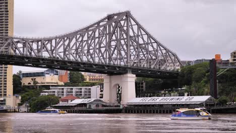 Fähren-Passieren-Den-Brisbane-River-Vor-Howard-Smith-Wharves-Mit-Der-Story-Bridge-Von-New-Farm-River-Walk-Aus-Gesehen