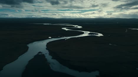 Drone-aerial-of-a-twisting-snakelike-river-in-the-cool-dark-of-the-ominous-clouds
