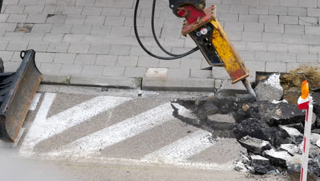 Martillo-Hidráulico-De-Excavadora-Rompiendo-La-Superficie-De-La-Carretera-Asfáltica-En-El-Sitio-De-Reconstrucción