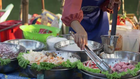 Dieses-Ansprechende-Archivmaterial-Zeigt-Eine-Thailänderin,-Die-Sorgfältig-Zutaten-Für-Ihr-Essen-Auf-Dem-Geschäftigen-Schwimmenden-Markt-In-Hat-Yai,-Thailand,-Vorbereitet.