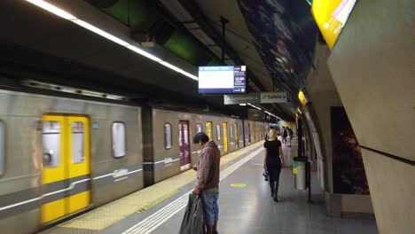 People-inside-underground-railway-station-yellow-metallic-silver-train-arrive-at-Buenos-Aires-City-Once-Neighborhood-Argentina