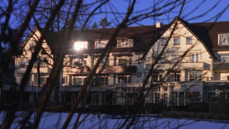 Spying-through-trees-at-Bilderberg-hotel-in-winter-landscape-with-sunlight-reflection