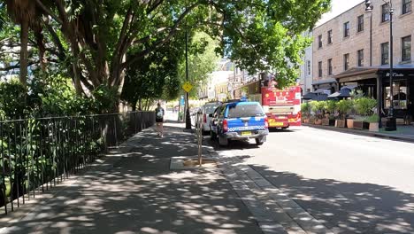 Día-Soleado-En-Una-Calle-De-Sydney-Con-Turistas-Explorando-En-Un-Autobús-De-Dos-Pisos,-Presencia-Policial-Visible