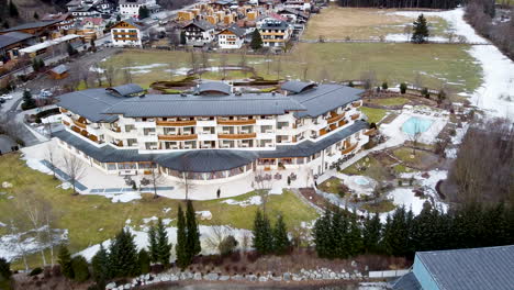 A-drone-approaches-a-luxury-Alpine-hotel-and-grounds-in-winter