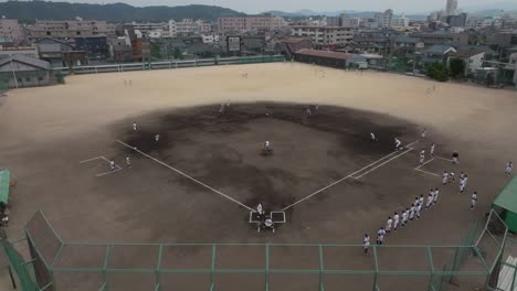 Toma-Aérea-De-Gran-Angular-Sobre-Un-Campo-De-Béisbol-Geométrico-Con-Estudiantes-Jugando-Un-Partido.