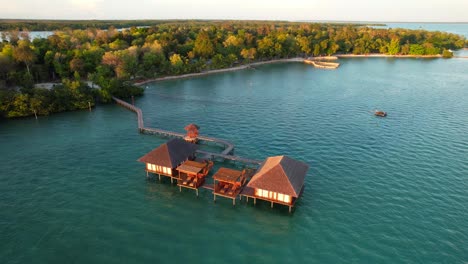 Dos-Exóticos-Bungalows-Sobre-El-Agua-Con-Terrazas-Para-Broncearse-Y-Un-Largo-Muelle-Que-Conecta-Las-Villas-Con-La-Isla-Leebong,-Belitung-Indonesia---Paralaje-Aéreo