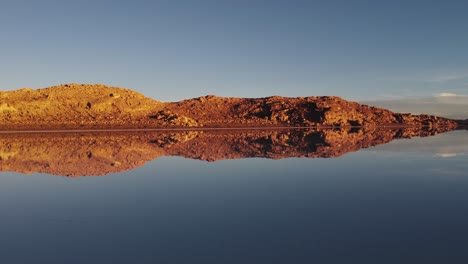 Paisaje-Rocoso-Dorado-Del-Altiplano-Reflejado-En-El-Salar-De-Uyuni,-Bolivia