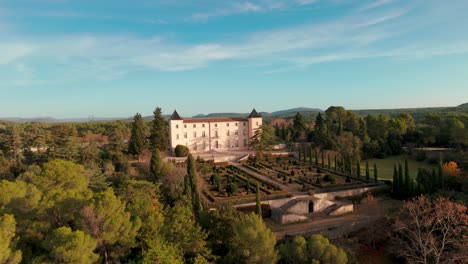 Aerial-view,-french-architectural-mansion,-scenic-garden-during-sunset