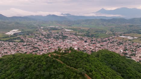 Cerro-De-La-Cruz-De-Tecalitlán:-Panorama-Aéreo-De-Picos,-Valle-Y-Volcán-Colima-En-Medio-De-Un-Cielo-Azul-Nublado