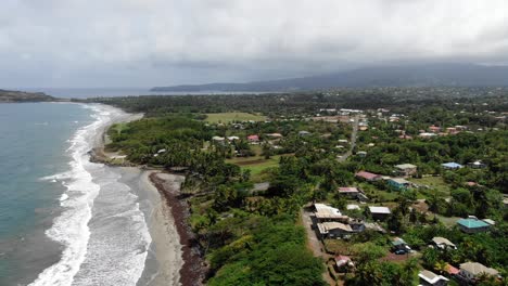 The-lush-pearls-airport-area-in-grenada-with-beach-and-waves,-overcast-sky,-aerial-view