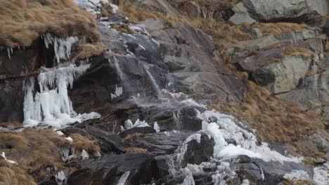 Wind-blows-across-jagged-mountain-slope-pushing-cascading-water-sidewards
