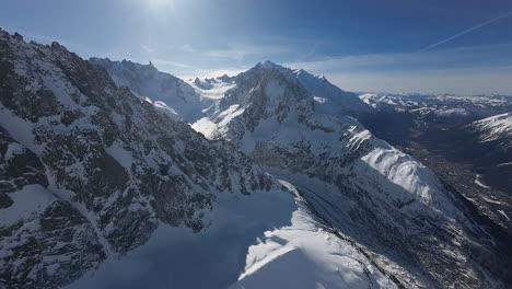 Aerial-view-of-snow-covered-alpine-mountains-on-a-sunny-day-with-clear-blue-sky,-close-to-Mont-Blanc-in-Chamonix-region