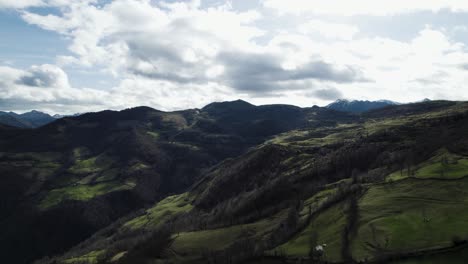 Ein-Dunkler-Schatten-Wird-über-Eine-Bergige-Grüne-Landschaft-Geworfen,-Während-Sich-Wolken-Am-Himmel-Zusammenziehen