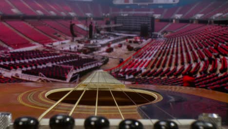 Macro-lens-view-of-acoustic-guitar-pushing-in-along-the-neck-with-a-background-of-a-time-lapse-video-of-crew-members-putting-together-a-stage
