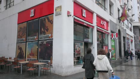 Pedestrians-walk-past-the-Kentucky-Fried-Chicken-restaurant,-the-American-fast-casual-chicken-chain,-in-Spain