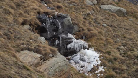 Formación-Rocosa-En-Medio-De-La-Pendiente,-Un-Pequeño-Chorro-De-Agua-Cae-Sobre-Piedra