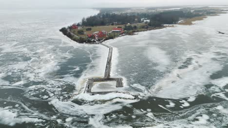 The-ventes-cape-and-frozen-curonian-lagoon-in-lithuania-during-winter,-with-a-lighthouse,-aerial-view