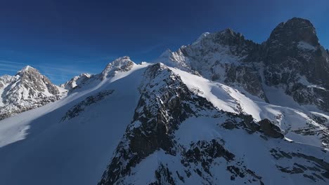 Impresionantes-Imágenes-Aéreas-De-Majestuosas-Montañas-Cubiertas-De-Nieve-Disfrutando-Del-Brillo-De-Un-Cielo-Despejado-Y-Soleado.