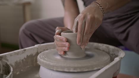 Close-up-of-hands-shaping-clay-on-a-pottery-wheel-with-focus-and-precision,-indoors,-during-the-day