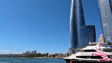 Tilt-down-view-of-Barangaroo-Point-buildings-with-Sydney-Harbour-tourist-boat-coming-into-view