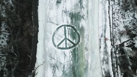 A-Static-4k-Shot-of-a-Large-Overhead-Plowed-Snow-Peace-Sign-on-Frozen-Ice-River-Outdoors