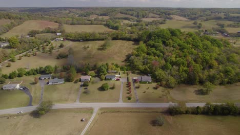 Aerial-trucking-shot-of-rolling-hills-of-Tennesee,-southeast-USA-rural-landscape-with-fields-and-farms-in-early-autumn