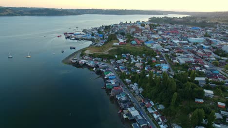 Panorama-Luftdrohnen-Sonnenuntergang-über-Der-Bucht-Von-Pedro-Montt-Palafitos-In-Castro,-Sonnenuntergang,-Unberührtes-Wasser-Mit-Patagonischer-Inselstadt