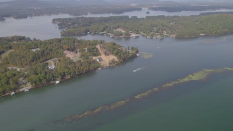 Aerial-orbit-over-Guntersville-Lake-near-Scottsboro,-AL-during-the-autumn-with-speed-boat-driving-through