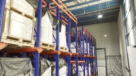 Inside-a-warehouse:-many-shelves-laden-with-neatly-stacked-pallets,-anonymous-containers