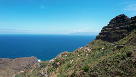 La-Gomera-Island,-Spain:-An-aerial-view-of-a-curvy-road-winding-through-tall-mountain-peaks-with-the-ocean-in-the-background,-Spain