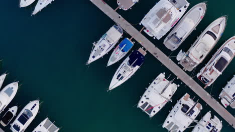 Vista-De-Arriba-Hacia-Abajo-De-Un-Puerto-Lleno-De-Gente-En-El-Mar-Adriático-En-Croacia,-Estacionamiento-De-Barcos,-Veleros,-Lanchas-Rápidas,-Lanchas-Motoras,-Muelle,-Aguas-Azul-Oscuro,-Turismo,-Viajes,-Vacaciones-De-Verano,-Deportes-Acuáticos